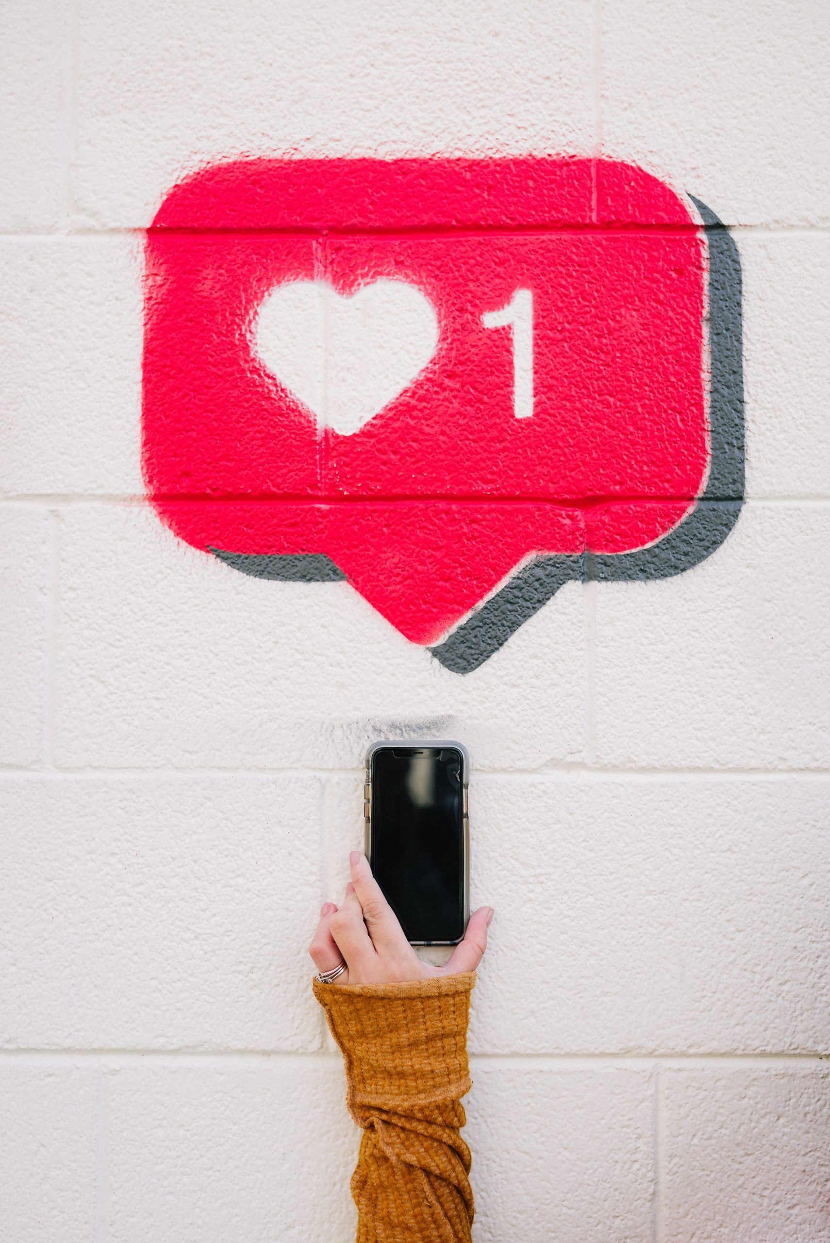 Hand holding cell phone with wall art that shows an Instagram like