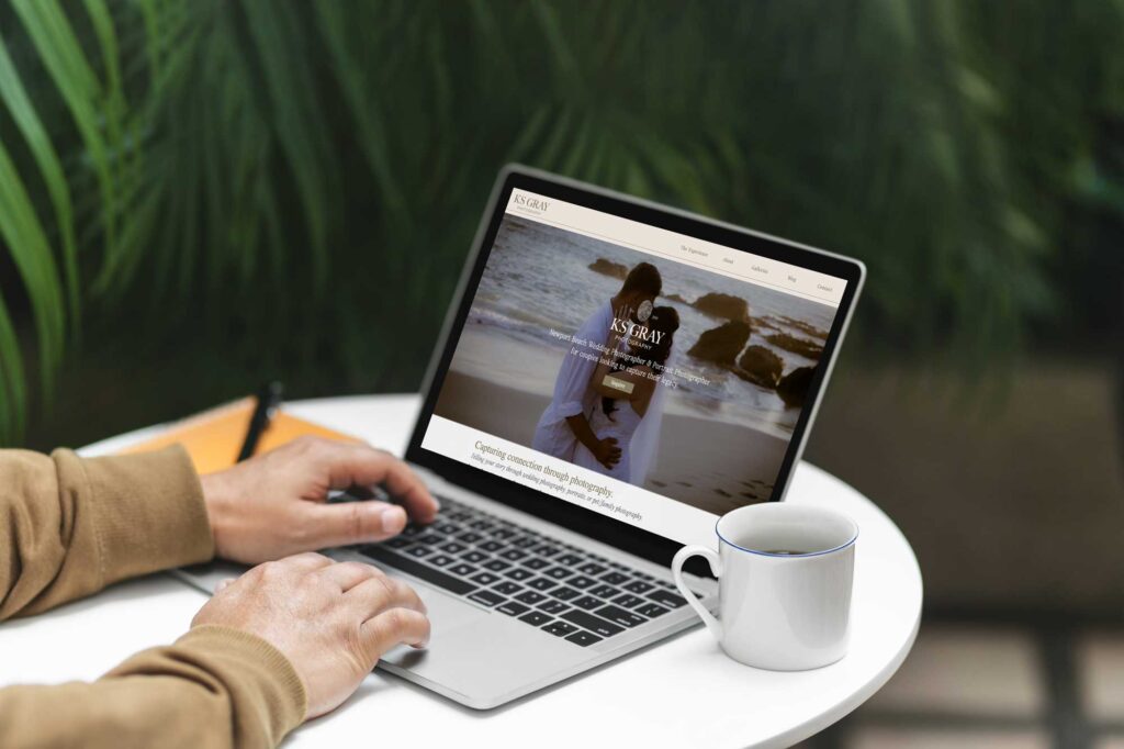 man looking at laptop with photographer website on it, and coffee cup next to the laptop
