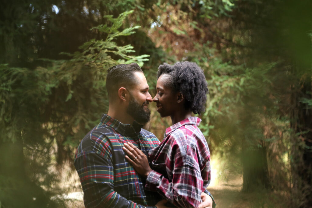 white man and Black woman kissing during an engagement shoot in the woods