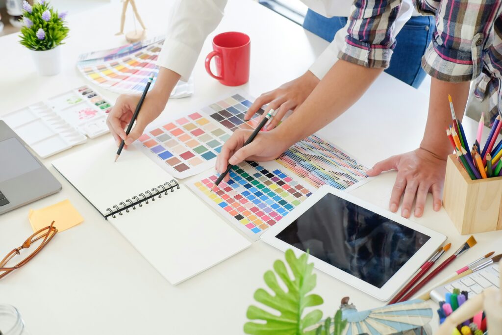 Two designers working at a desk with color swatches, pencils, and an iPad during a branding process