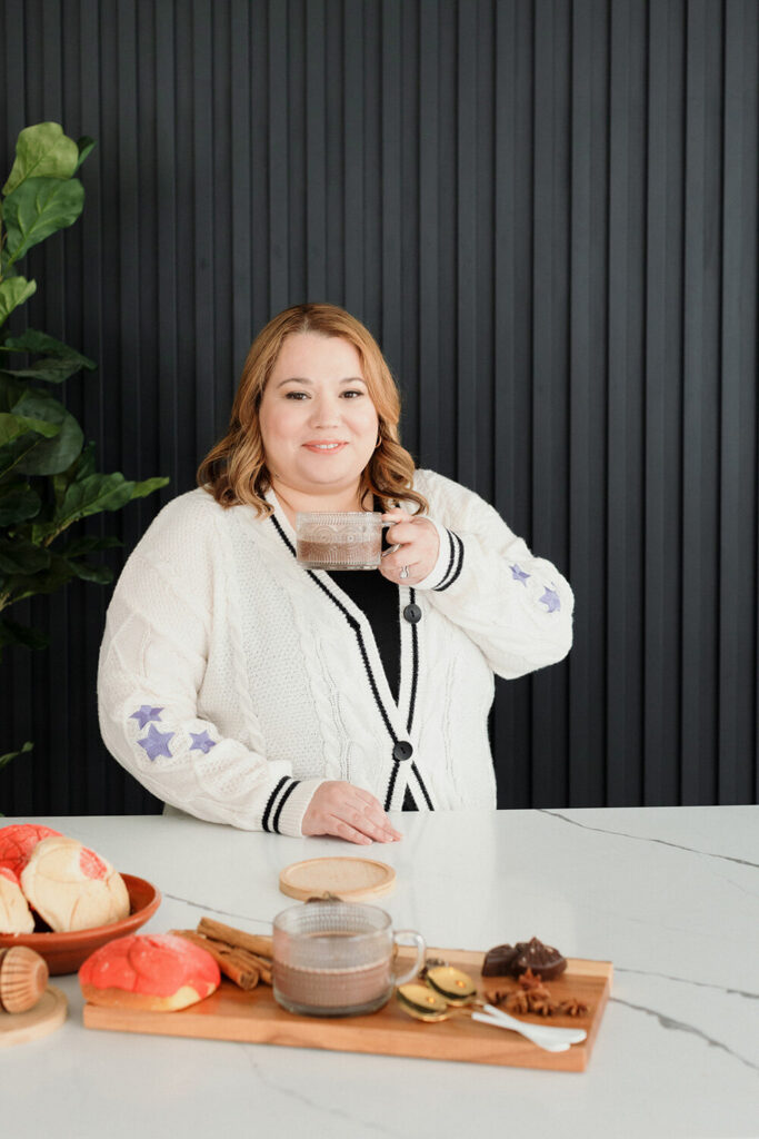 Cinthia holding a mug, and pastries on the counter top