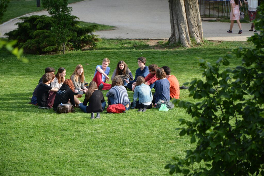 Group of people sitting down the ground discussing