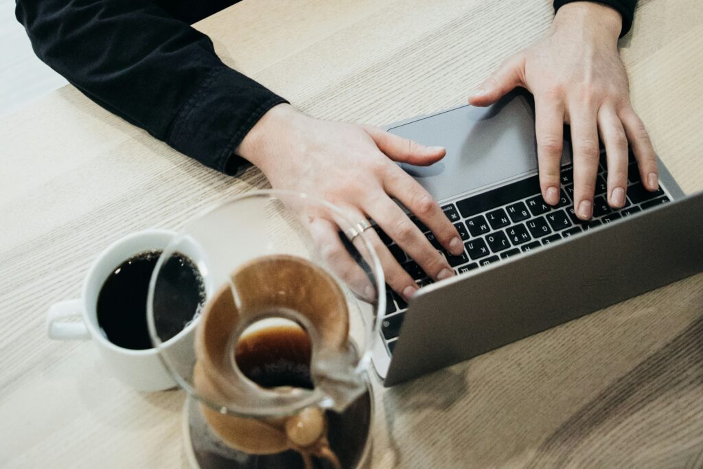 Hands working on the table with mug and coffee beside it