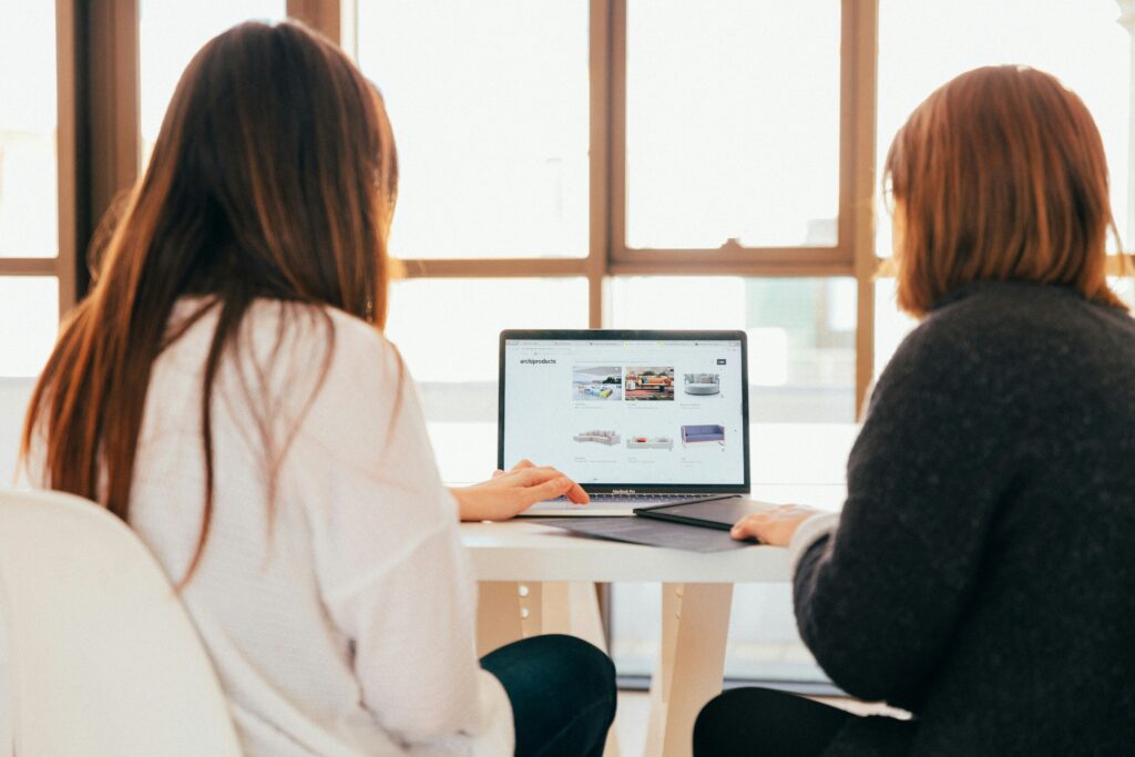 Two people talking in front of a laptop