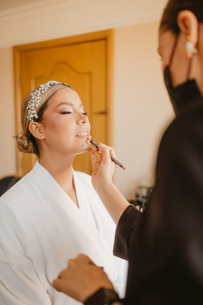 Bride getting makeup done with artist applying lip liner
