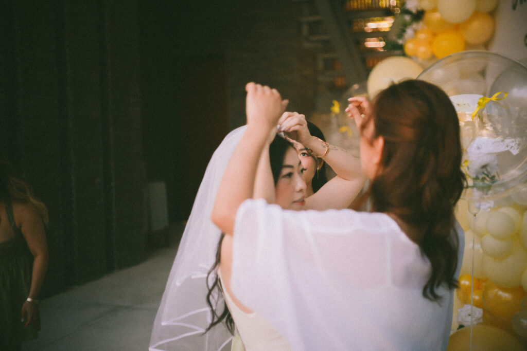 Bride having veil adjusted during wedding preparation