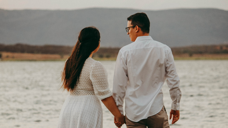 Couple holding hands while walking by the beach