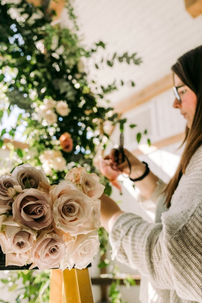 Wedding florist arranging flowers and decor behind the scenes