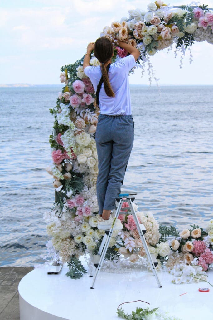 Wedding florist arranging flowers and decor behind the scenes