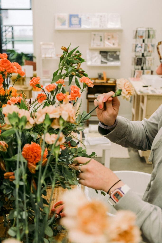 Florist trimming flowers in a bright studio
