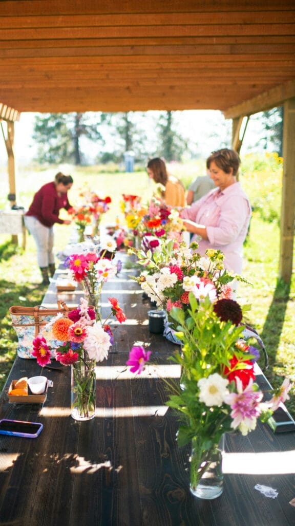 Florists arranging colorful flowers together at an outdoor event table
