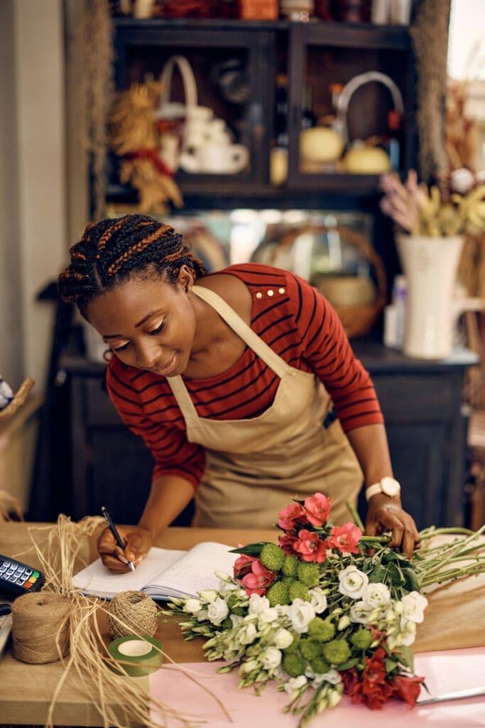 Florist arranging flowers and writing notes at a worktable
