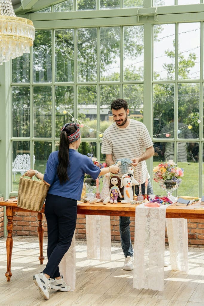 Two vendors talking beside a table of handmade products and floral arrangements