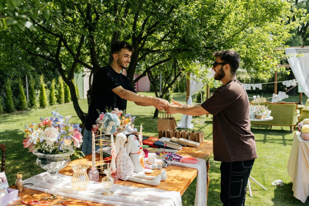 Two vendors exchanging a small bag at an outdoor market table