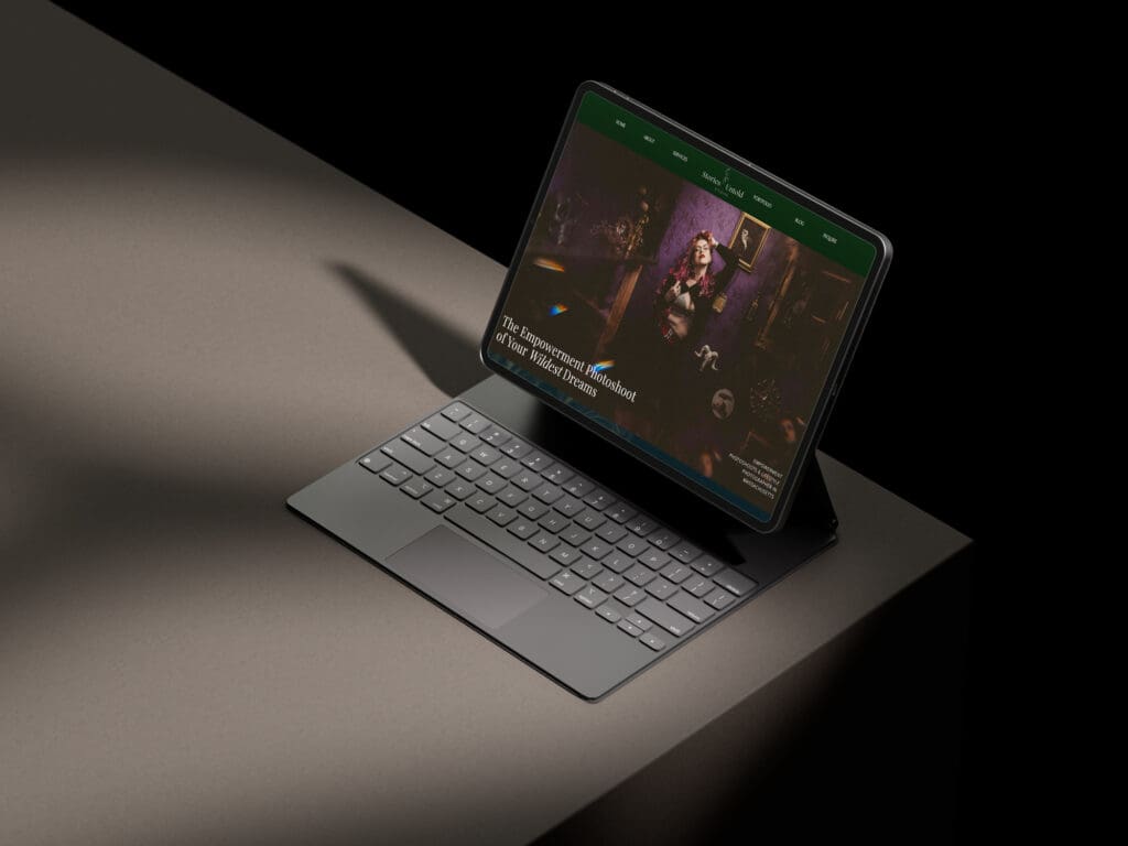Tablet and keyboard showing a dark photography website mockup
