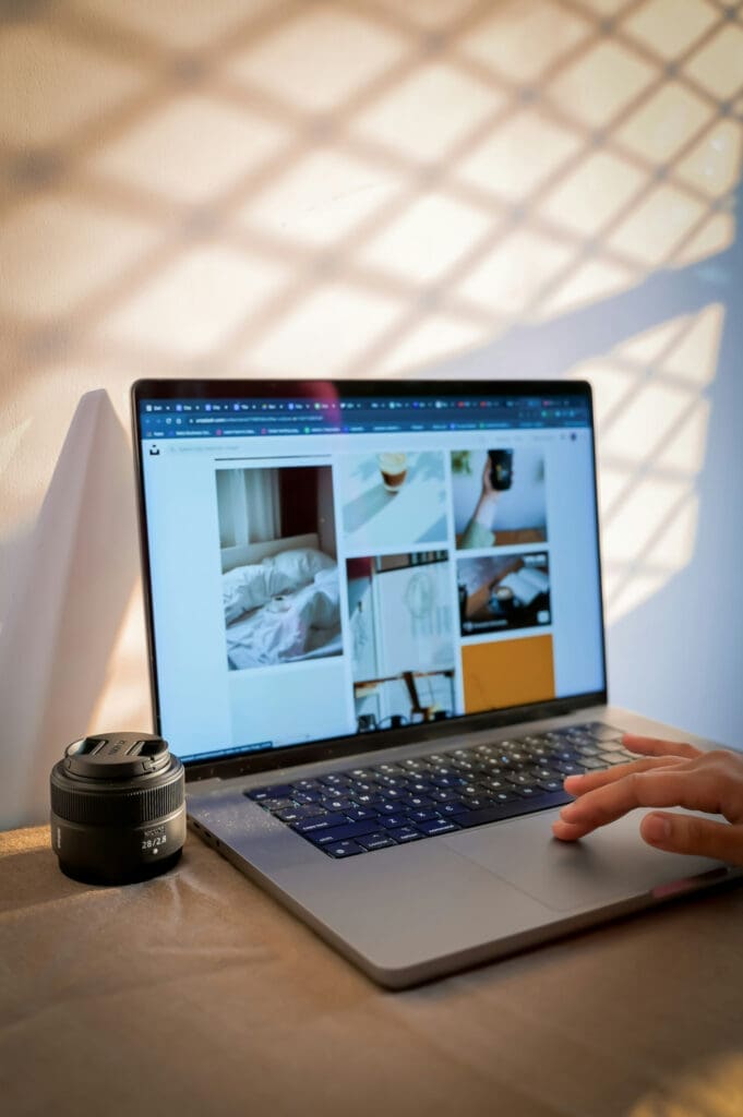 Laptop showing a photo gallery with a camera lens beside it