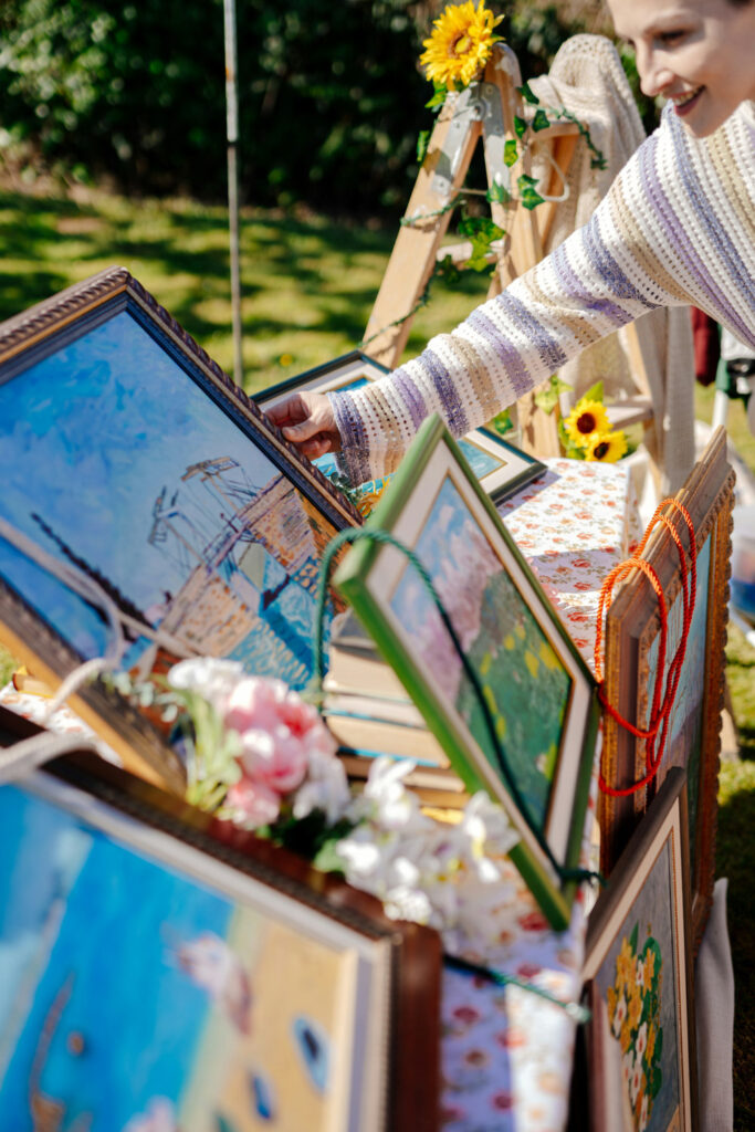 Woman arranging framed paintings at an outdoor display