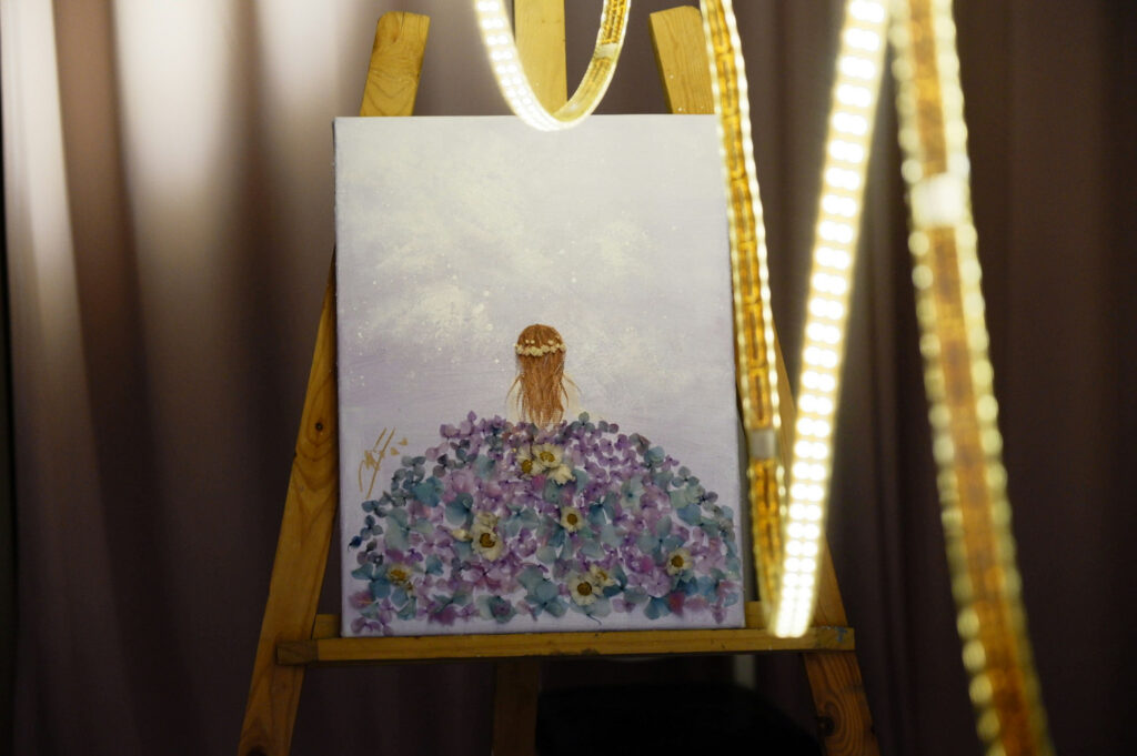 Painting displayed on an easel with decorative lights