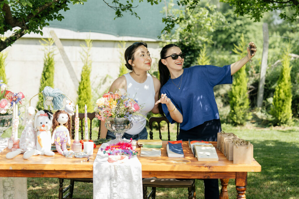 Two vendors taking a selfie at an outdoor event table