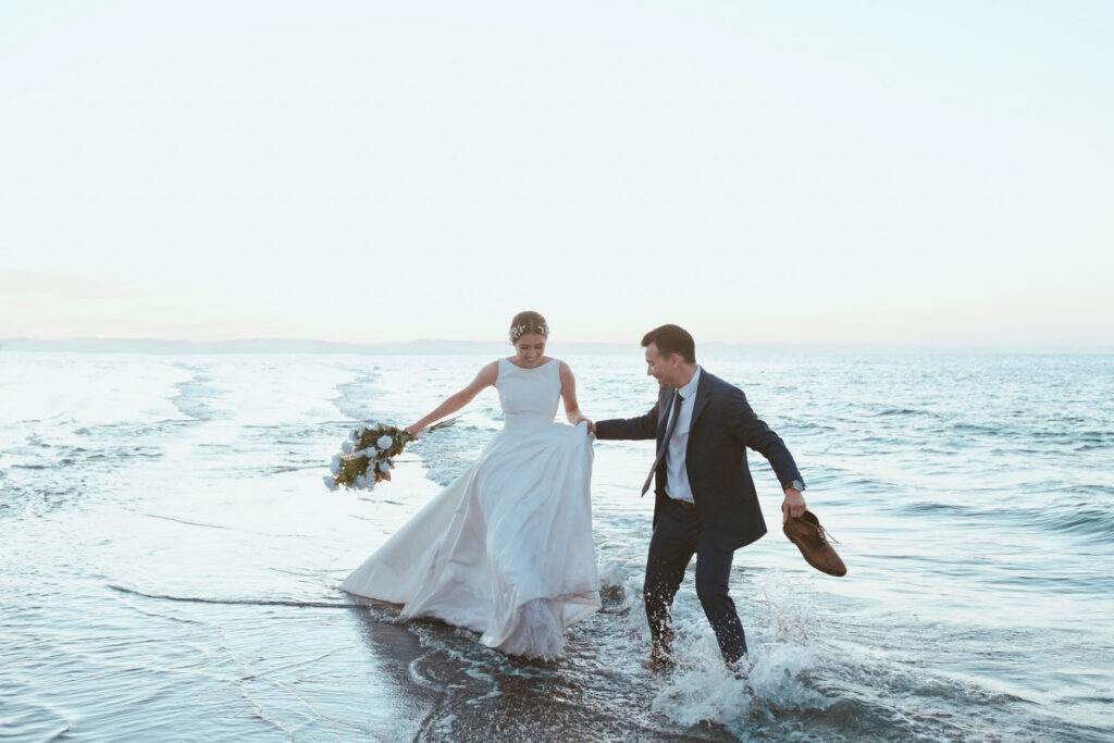 Bride and groom walking along the ocean