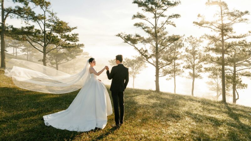 Bride and groom walking through a sunlit forest.