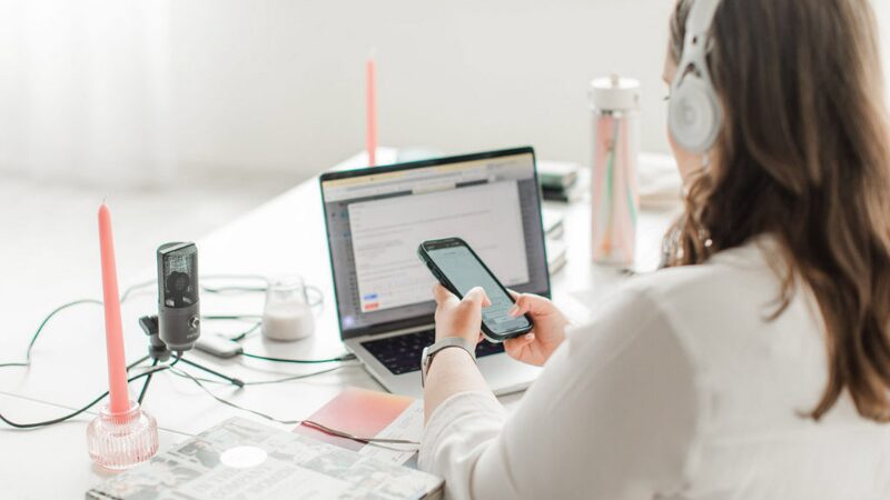Emily working at a desk with headphones, laptop, and microphone